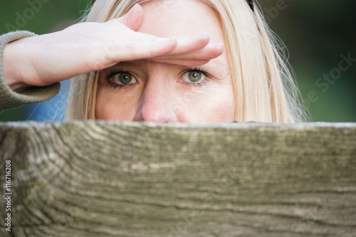 Obraz na plátně Frau beobachtet versteckt über Zaun