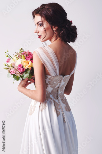 Woman in wedding dress with flowers' bouquet.
