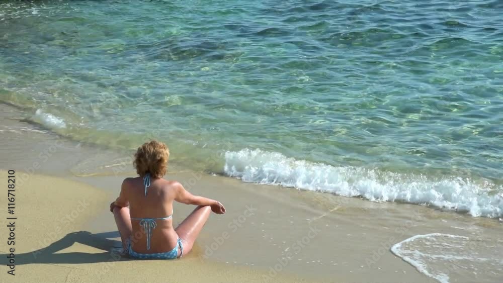 Woman in bikini sunbathing, enjoying, relaxing and meditating on the sandy beach Woman in bikini sunbathing, enjoying, relaxing and meditating on the sandy beach
