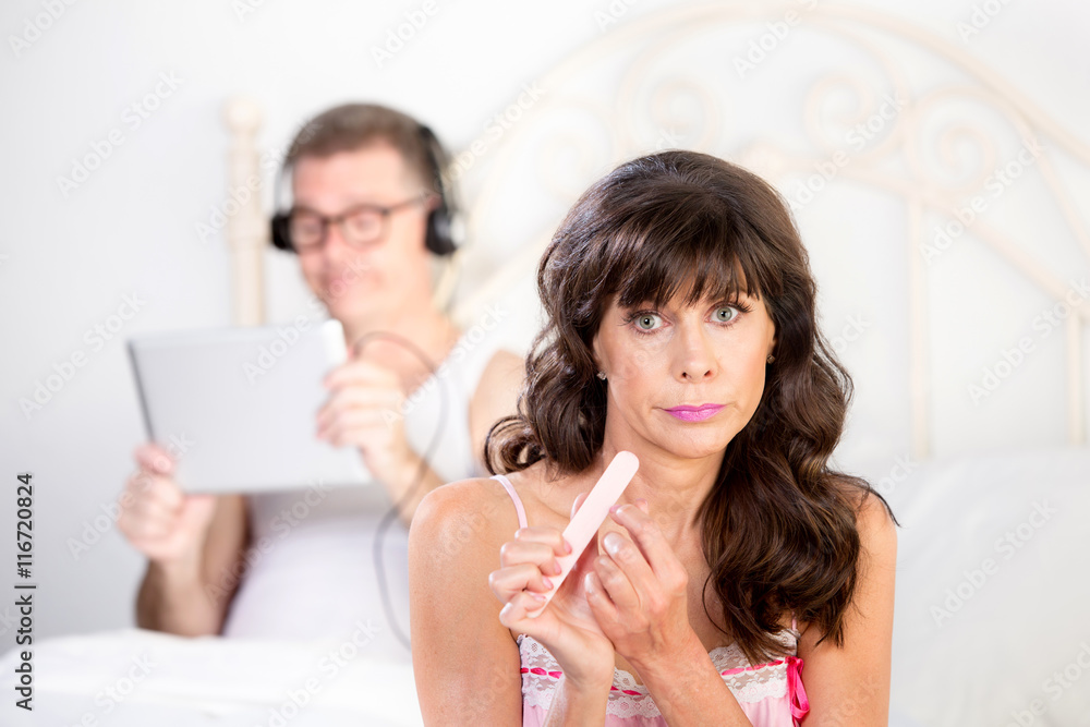 Upset Woman Gestures Regarding Man in Bed with Computer Tablet Upset Woman Gestures Regarding Man in Bed with Computer Tablet