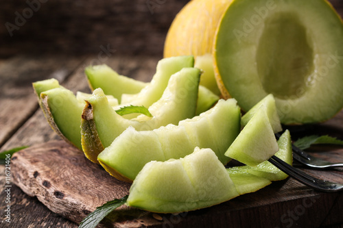 Fresh melons sliced and mint on wooden table, healthy food