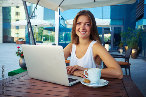 Portrait of smiling lady sitting on café open terrace with lapt © ArtFamily