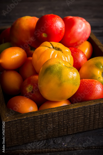 Red and yellow tomatos in wooden box.