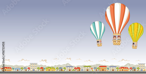 Cartoon kids inside a hot air balloon flying over a suburb neighborhood of a colorful city. 


