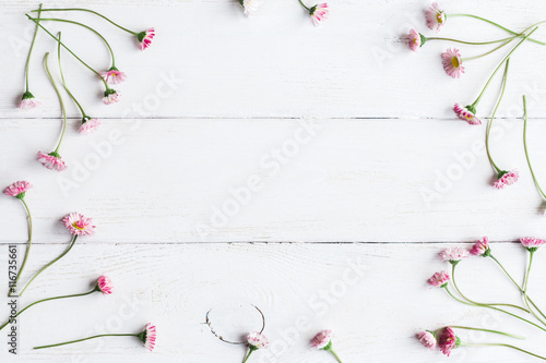 frame of daisy flowers on wooden white background, top view, flat lay