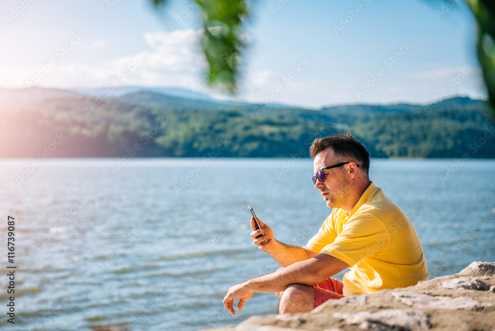 Man sitting on a beach and using smart phone