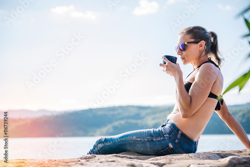 Woman relaxing by the sea and drinking coffee