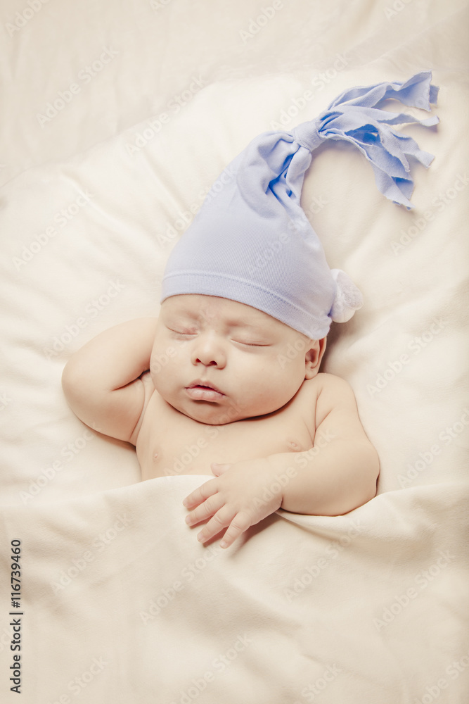 Newborn baby wearing ligt blue hat sleeping inside soft bed Newborn baby wearing ligt blue hat sleeping inside soft bed
