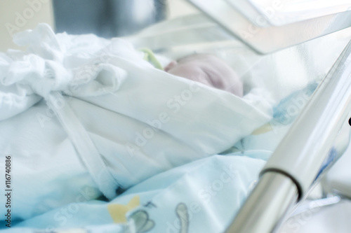 newborn child sleeping in translucent plastic crib