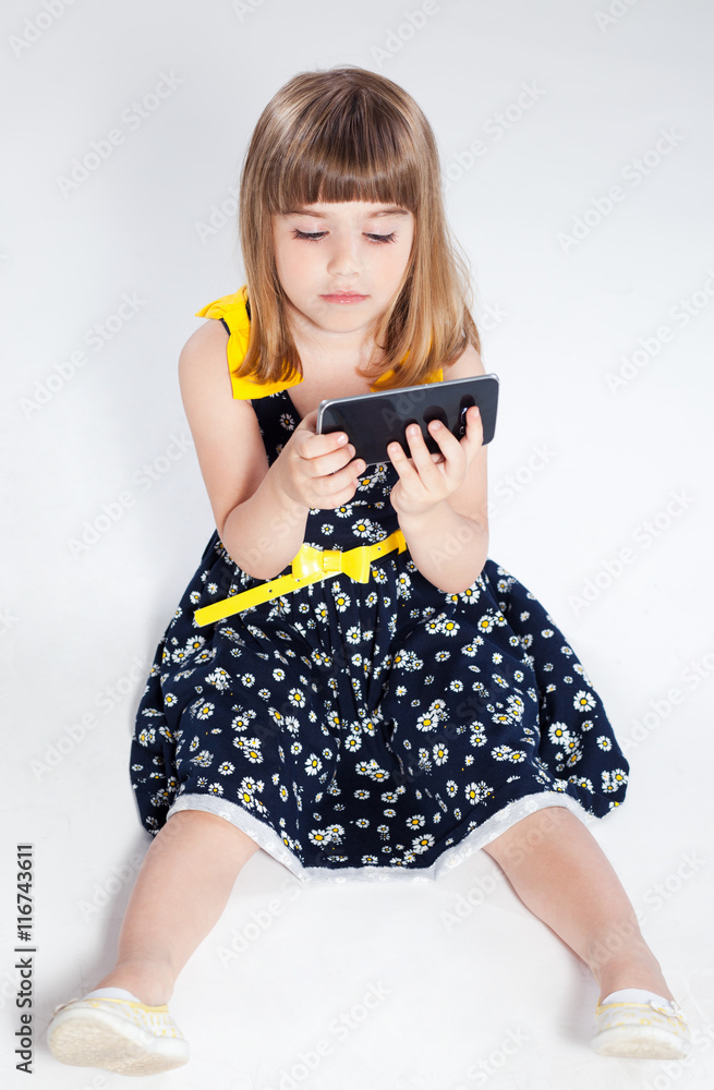 Pretty little girl in studio on gray background. Girl using mobile phone isolated Pretty little girl in studio on gray background. Girl using mobile phone isolated