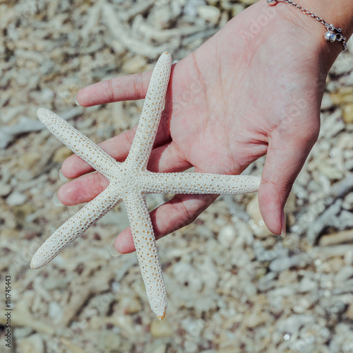 Closeup of Star fish in girl 's hand at tropical beach. Journey