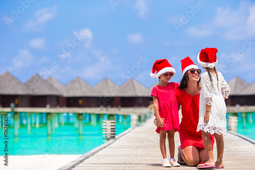 Young mother and little girls in Santa hat on Christmas holidays