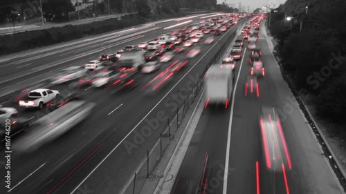 Time Lapse of traffic where the footage has been made black and white except for the red of the car's taillights.