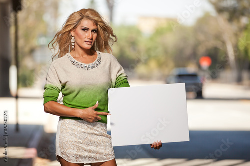 Obraz na płótnie Latina Transgender female pointing at blank poster board sign