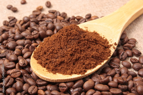 Ground coffee in a wooden spoon close-up on a background of coff