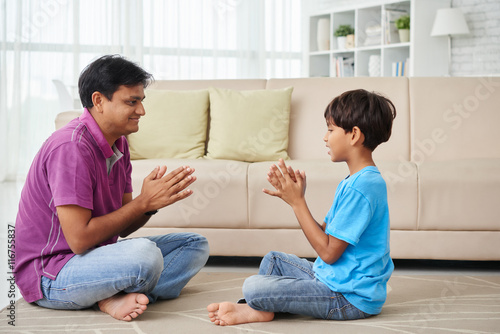 Indian father and son sitting on the floor and playing