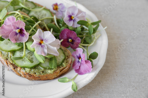 avocado , cucumber, sunflower sprout and edible flowers on sourdough toast, healthy plant based diet