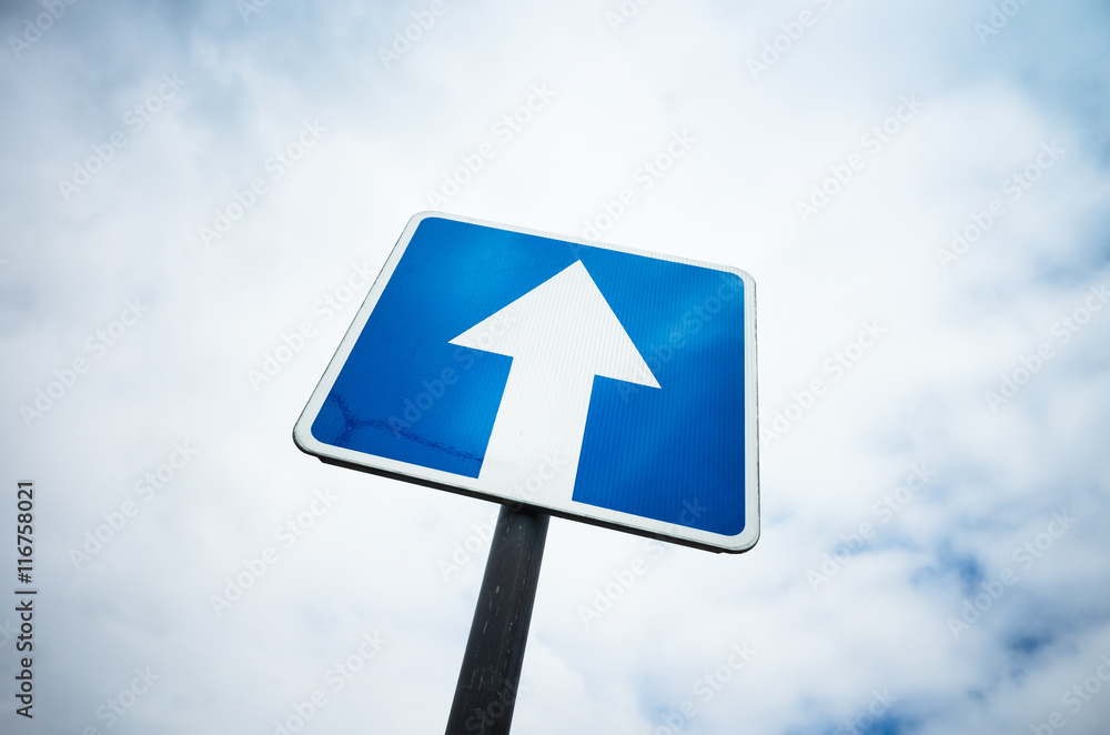 One way street, blue road sign over sky background One way street, blue road sign over sky background