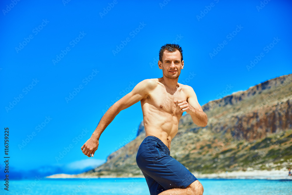 strong athletic man with bared torso running on the beach along the sea front strong athletic man with bared torso running on the beach along the sea front