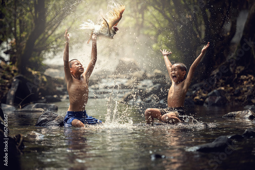 Boys playing with their duck in the creek