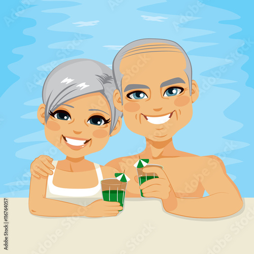 Lovely senior couple drinking green cocktails relaxing on pool enjoying retirement vacation time together