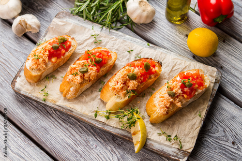 Toasts with cooked fish meat. Lemon and garlic. Salmon bruschetta with tomatoes. Recipe of meal with seafood.