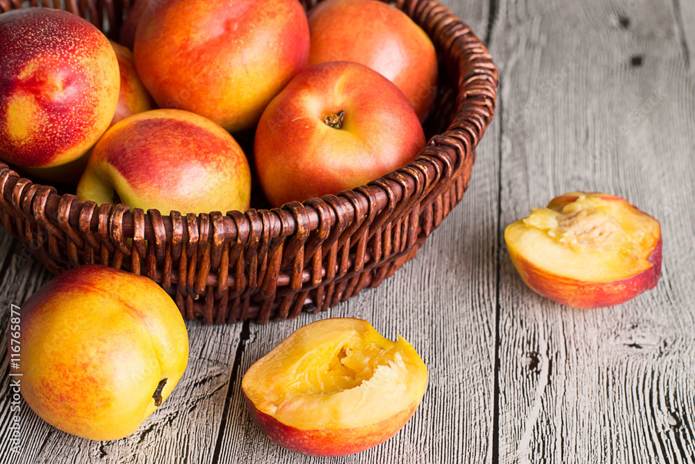 Nectarines. Ripe juicy nectarines in a wicker basket on a gray wooden table. Nectarines. Ripe juicy nectarines in a wicker basket on a gray wooden table.
