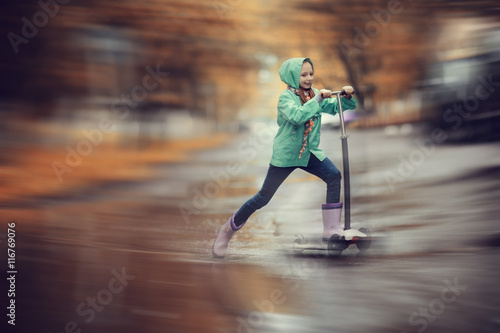 girl on scooter rides through the puddles © kichigin19