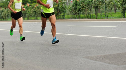 Unidentified marathon athletes legs running on city road