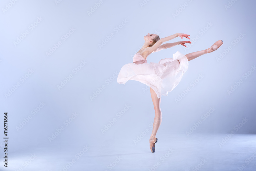 Ballet Perfection. Young and beautiful ballerina is dancing in a white studio full of light. - obrazy, fototapety, plakaty 