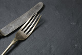 Antique silver knife and fork on a rustic slate background