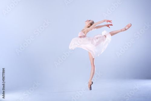 Ballet Perfection. Young and beautiful ballerina is dancing in a white studio full of light.