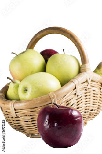 closeup of a red apple with back basket full of fruits. 