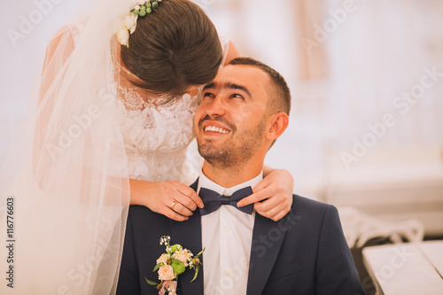 Happy couple of newlyweds valentynes posing and hugging in old europeand street with bouquet. Vintage cafe. Newlywed kiss. Groom in glasses. photo