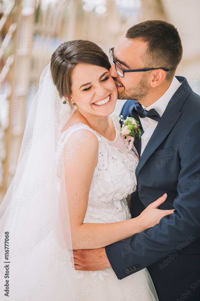 Happy couple of newlyweds valentynes posing and hugging in old europeand street with bouquet. Vintage cafe. Newlywed kiss. Groom in glasses. Happy couple of newlyweds valentynes posing and hugging in old europeand street with bouquet. Vintage cafe. Newlywed kiss. Groom in glasses.