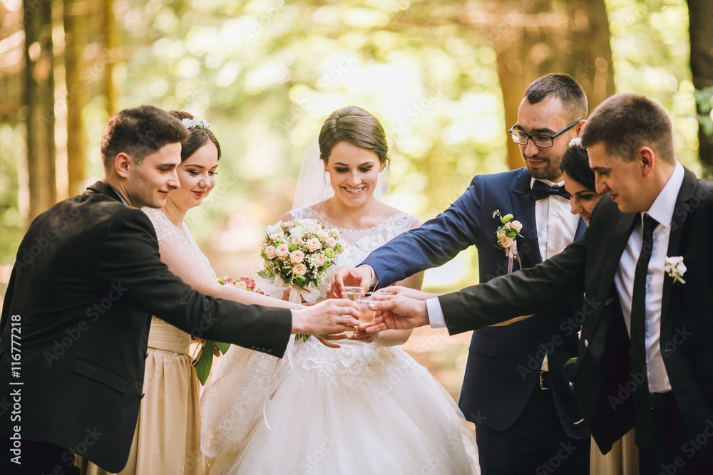 bride and groom with happy groomsmen and bridesmaids having fun and popping champagne, hilarious moment. Funny guys