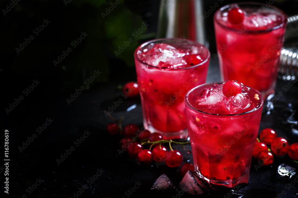 Red currant drink with ice, black background, selective focus Red currant drink with ice, black background, selective focus