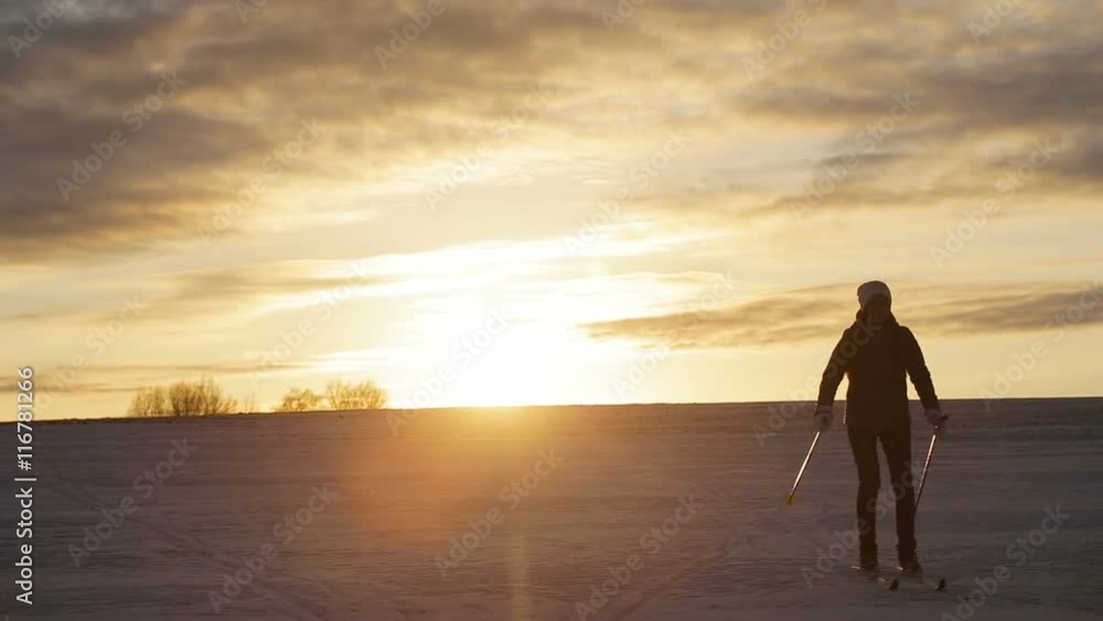Girl on cross-country skis in the field.Skiing in field in cold winter day.Cross-country skiing on field in the sunny day.Skier, cross-country skiing in the field at sunset. Girl on cross-country skis in the field.Skiing in field in cold winter day.Cross-country skiing on field in the sunny day.Skier, cross-country skiing in the field at sunset.