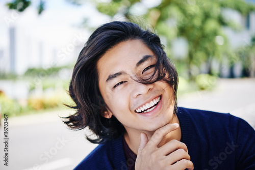 Tableau sur toile Face of cheerful handsome Vietnamese man outdoors