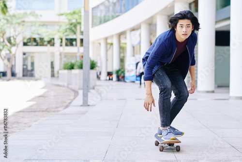 Vietnamese young guy skateboarding in the city