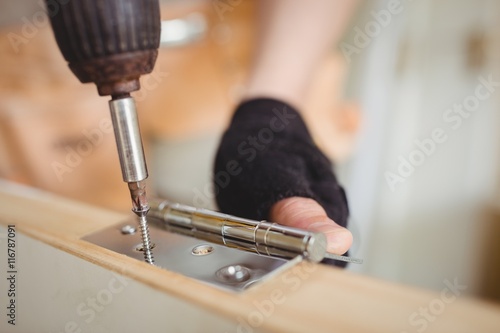 Carpenter tightening screw to hinges on a wooden door