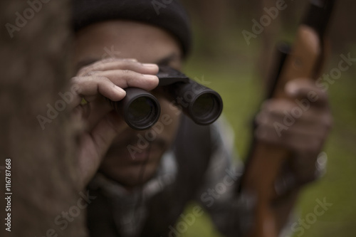 Interracial hunter in the forest looking through binocular