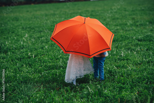 little boy and girl under red umbrella