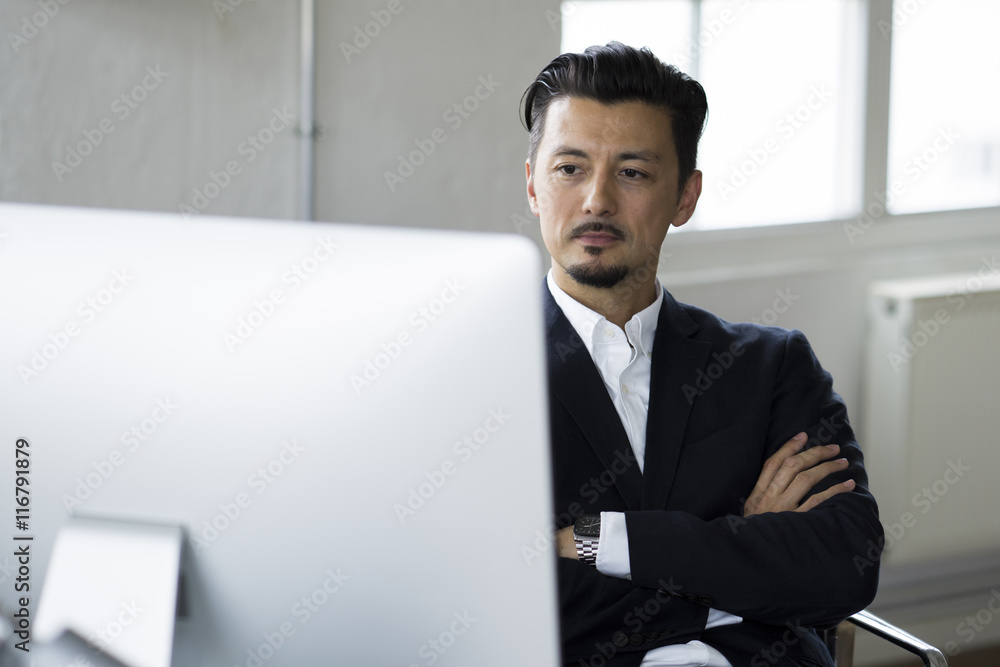 Businessman sitting in office, working on computer Businessman sitting in office, working on computer