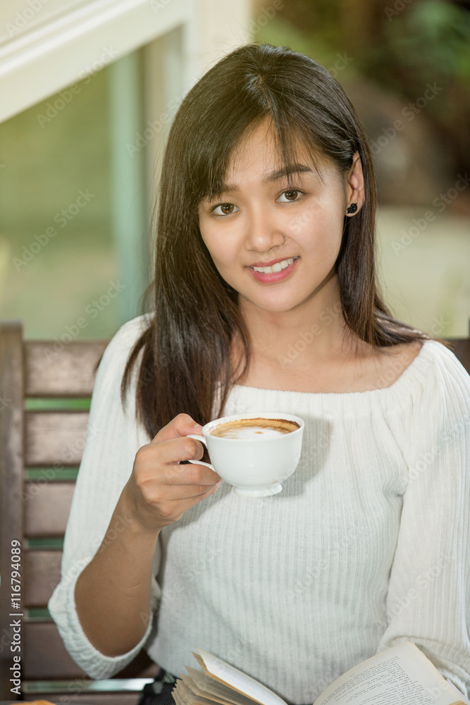 asian woman drink coffee and reading book in garden asian woman drink coffee and reading book in garden