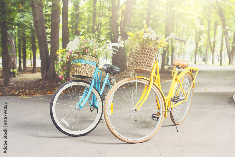 Yellow and turqoise city woman bicycles with flowers in park Yellow and turqoise city woman bicycles with flowers in park