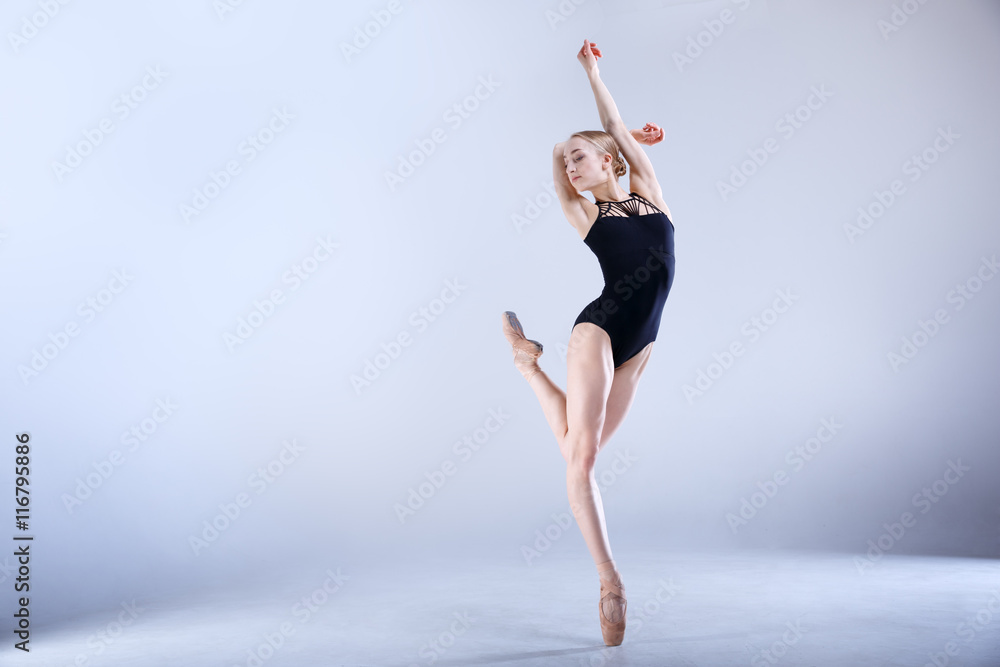 Ballet Perfection. Young and beautiful ballerina is dancing in a white studio full of light.