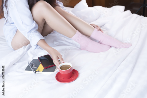 Young Asian woman sitting on a bed wearing socks