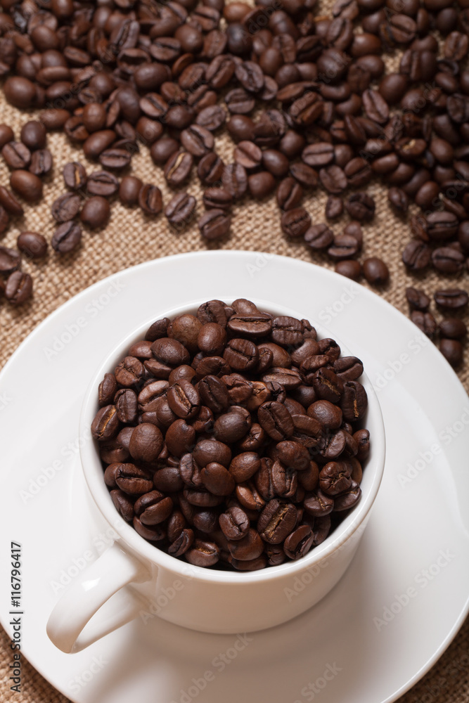 Fototapeta premium Coffee beans and coffee in cup on burlap. Selective focus
