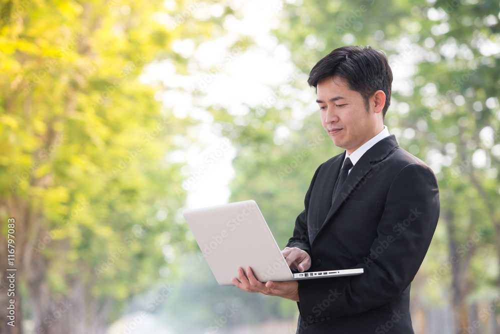 Happy business man using computer outside on in park . Happy business man using computer outside on in park .